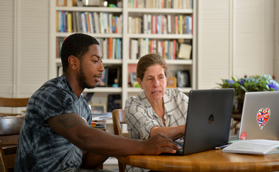 student and professor pointing to computer